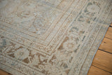 Distressed Mahal carpet corner, showcasing worn platinum and beige pile, machine-bound edge.