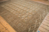 Vintage distressed Bokhara carpet corner showing geometric guls, rhythmic border, and even wear.