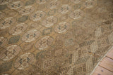 Distressed vintage Bokhara carpet showing repeating geometric guls and detailed borders in muted tones.