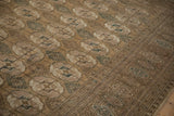 Distressed vintage Bokhara carpet featuring geometric guls, hook and latch diamonds, and border details.