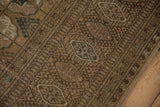 Distressed vintage Bokhara rug's intact side selvage, showing brown and pale olive geometric patterns.
