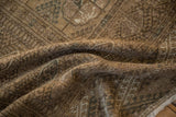 Distressed vintage Bokhara rug close-up: geometric patterns, soft pile, and pale brown, olive hues.
