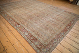 Distressed vintage Qom carpet showing parallel columns of botehs and a chestnut floral palmette border.