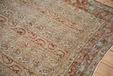 Corner of a distressed Persian Qom with a chestnut floral border and repeating boteh pattern.