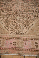 Decorative wear on the pink and chocolate brown corner of a vintage distressed Persian carpet.