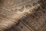 Softly folded vintage Persian carpet showing the distressed texture and dusty pink Herati design.