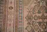 Detailed view of the distressed rug's hand-knotted texture in pink, slate blue, and brown.