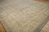 Angled view of a distressed Mahal carpet's rhythmic Herati field and samovar turtle border.