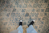 A close view of the distressed Joshegan carpet's even wear, low pile, and faded teal floral sprays.