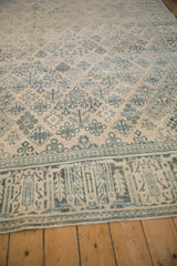 Detail of the distressed, low-pile texture and faded teal arabesque border pattern.