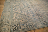The worn texture of a vintage Joshegan rug's dusty teal and sapphire blue arabesque border.