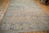 Angled view of a distressed Joshegan carpet with a faded, low-pile texture and dusty teal florals.