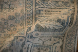 A folded vintage Joshegan rug showing the softly distressed texture and faded teal arabesque details.