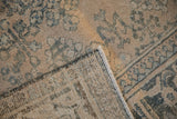 Corner of a distressed Joshegan rug folded to show the hand-knotted foundation and low pile.