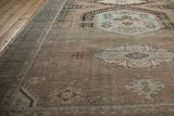 Angled perspective of the distressed vintage rug, detailing its low pile and sand and powder blue tones.