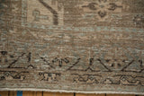 The distressed texture of a vintage Persian Veece carpet showing low-pile wear and a machine-bound side.