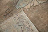 Folded corner of a distressed vintage Veece carpet showing the low pile texture and its machine-bound edge.