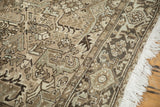 Vintage Heriz carpet showing worn pile, geometric motifs, and white fringe.
