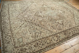 Low angle on a distressed Mehrivan carpet, showing its time-softened geometric pattern and neutral palette.