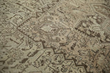 Low pile texture with even wear across geometric patterns in sand and charcoal.