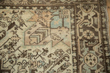 Corner of a distressed Mehrivan carpet showing geometric motifs in charcoal, sand, and dusty slate blue.