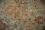 Distressed Bakhtiari carpet detail: stepped corner contour, dusty olive and terracotta floral motifs.