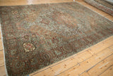 Distressed Bakhtiari carpet corner with palmette border, dusty olive, terracotta, and subtle foundation wear.