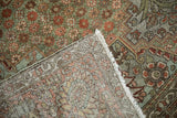 Distressed vintage Bakhtiari rug: olive and copper florals, with visible wear, foundation, and fringe.