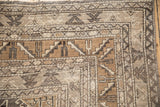 Layered borders showing geometric pawn motifs in charcoal, olive green, and ivory on a vintage Kars carpet.