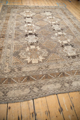 Full length view of a vintage distressed Kars carpet showing its earthy, geometric gul pattern.