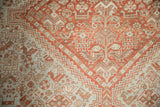 Stepped geometric relief and floral motifs in rust and dusty blue on a distressed vintage pile.