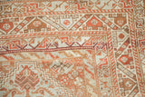 Worn knot heads and geometric pinwheel motifs in rust and blue on a distressed Shiraz carpet.