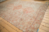Angled view of a vintage Shiraz carpet with interconnected triple diamond medallions and worn texture.