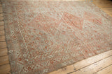 Low perspective on a distressed Shiraz carpet with muted rust and powder blue geometric patterns.
