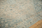 Low-pile texture of a distressed Qashqai carpet with pale slate blue motifs on a sand field.