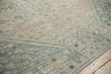Angled view of the time-softened texture on a distressed Qashqai carpet with pale blue details.