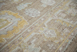 Distressed Afghani Oushak rug pile, featuring faded saffron, beige, and seafoam palmettes with wear.