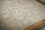 Distressed Afghani Oushak carpet corner showing textured side selvage and muted floral palmette motifs.