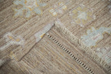 Close-up of distressed Afghani Oushak carpet pile with nuanced palmettes, wear, and braided side cord.
