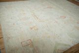 Distressed Afghani Moroccan carpet showing faded red, green, blue plant motifs on ivory.