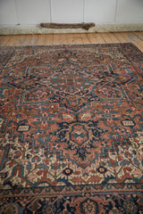 Heriz carpet displaying geometric floral blossoms, serrated leaves in brick red, navy, dusty pink.