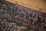 Vintage Heriz rug side border, geometric navy blue field, and dusty pink selvage.