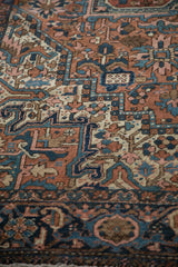 Vintage Heriz carpet detail: brick red field, geometric floral blossoms, and navy turtle samovar border.