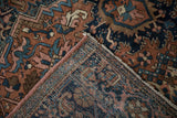 Folded vintage Heriz carpet corner, revealing geometric patterns and restored pink side cord.
