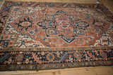 Vintage Mehrivan rug detail: brick red geometric field, navy floral motifs, serrated leaf border.