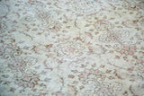 Vintage Oushak rug showing distressed texture with subtle ivory and muted pink floral motifs.