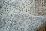 Distressed ivory Oushak rug pile texture and hand-knotted foundation with faded floral motifs.