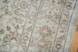 Distressed ivory Oushak rug, showcasing worn pile with subtle blush tone-on-tone floral motifs.