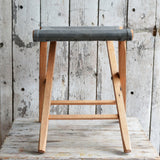 Stool's slate waxed canvas seat with visible stitching and reclaimed oak frame.