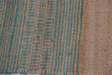 Gemma jute rug's textured weave with alternating natural beige and teal geometric lines.